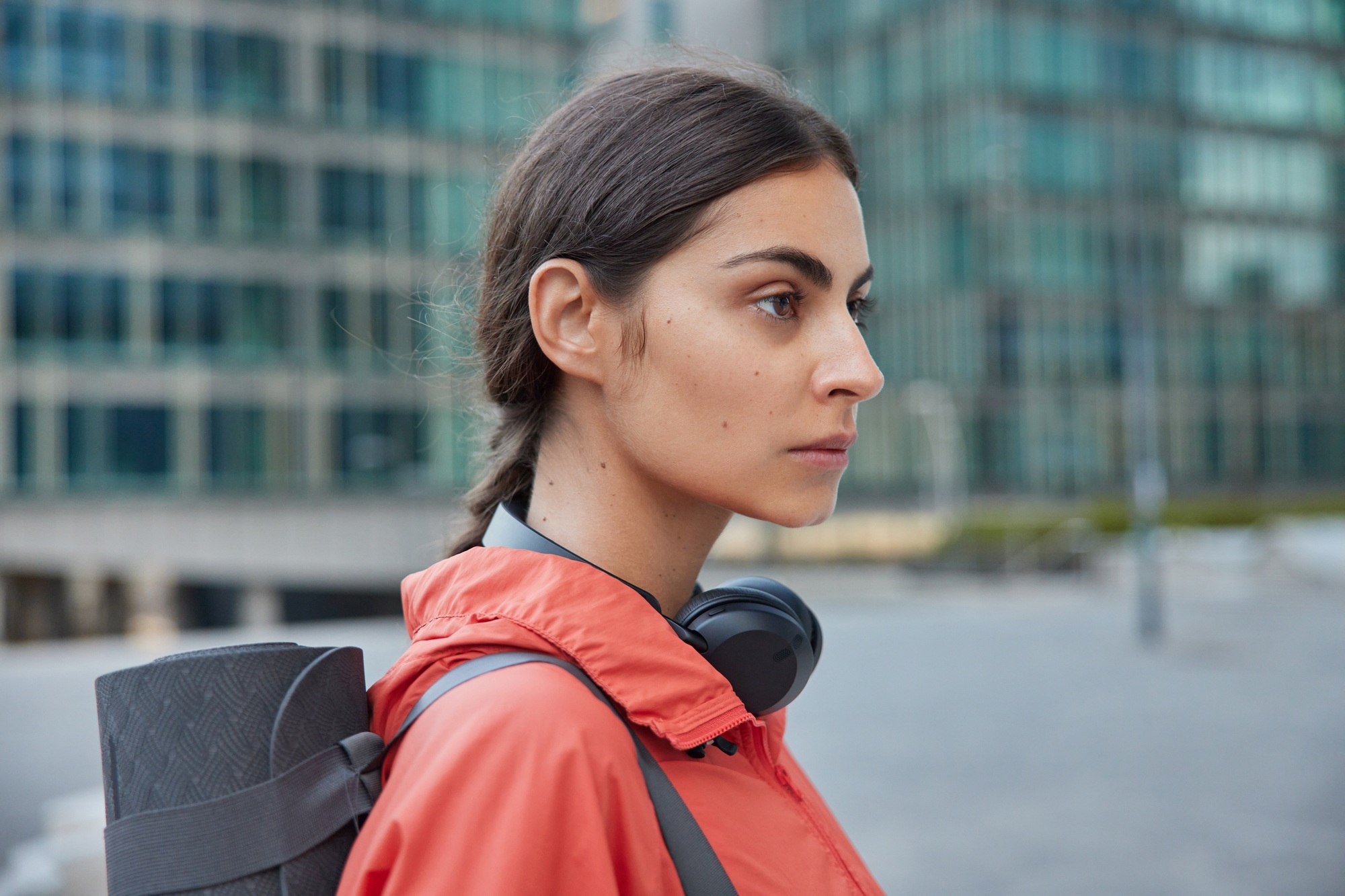 Profile shot of active young professional woman yoga instructor carries rubber karemat going to have